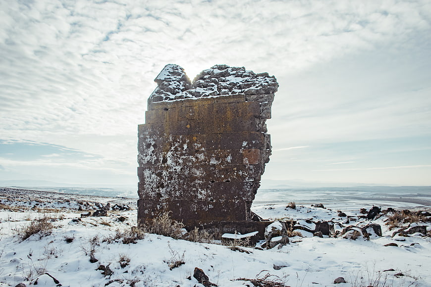 Ancient stone ruin standing in snowy winter landscape