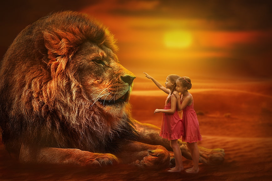 Two young girls reaching out to a giant lion at sunset