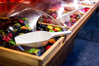 Colorful gummy candies in wooden bins with scoops