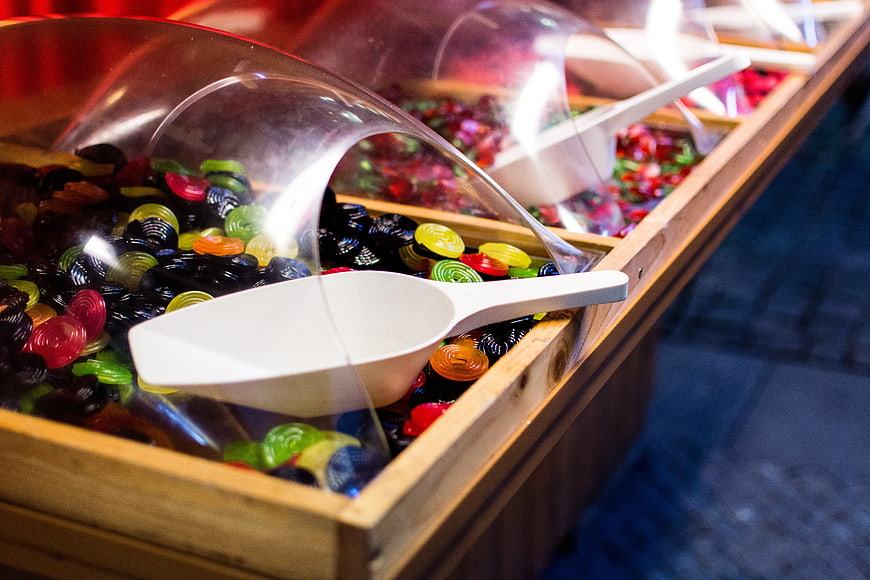 Colorful gummy candies in wooden bins with scoops