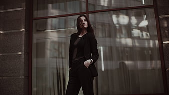 Confident businesswoman in black suit standing by office window