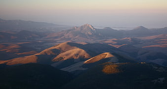 Golden hour view of rolling hills and distant mountains