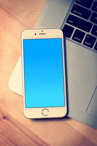 White Smartphone with Blue Screen on Laptop Keyboard