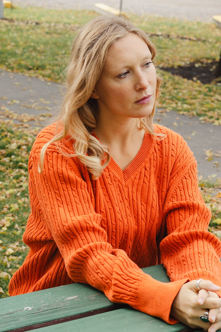 Woman in Orange Sweater Sitting on Park Bench in Autumn