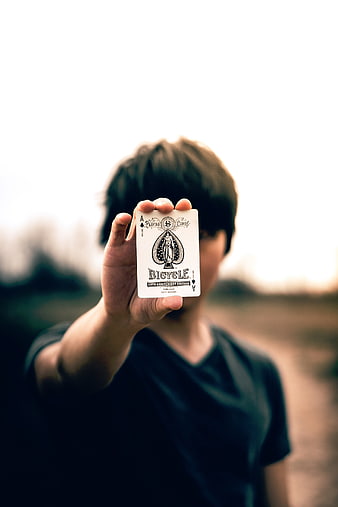 Man holding Ace of Spades playing card outdoors