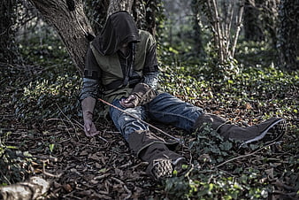 Hooded figure sitting in forest with self-harm scars