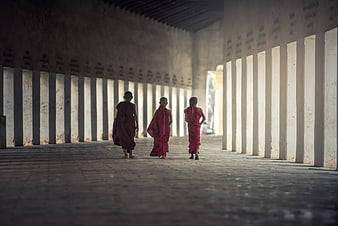 Three young Buddhist monks walking in a monastery hallway