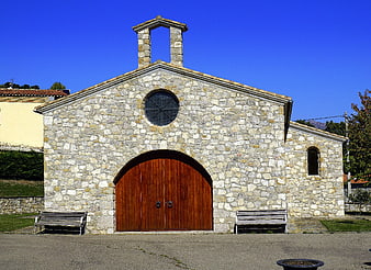 Stone chapel with wooden doors and blue sky
