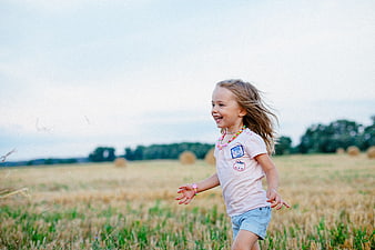 Happy little girl running through a golden wheat field