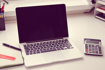 Silver laptop with calculator and pen on white office desk