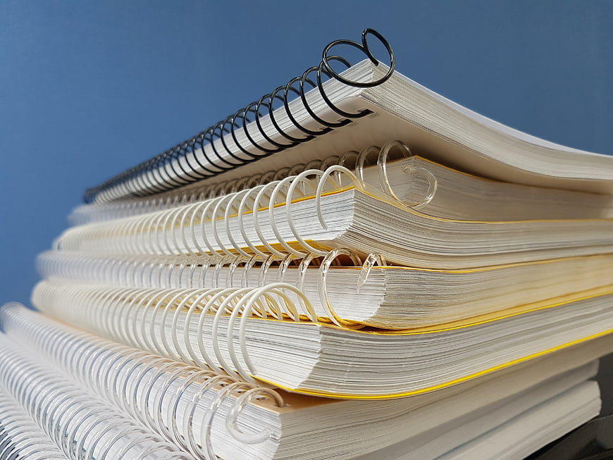 Stack of spiral notebooks on blue background