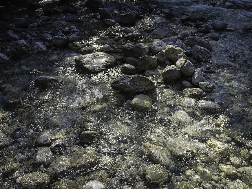 Clear stream flowing over gray rocks in nature