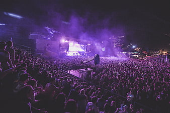 Large crowd at a vibrant purple night music festival concert