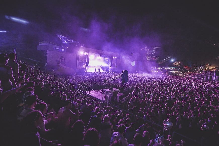 Large crowd at a vibrant purple night music festival concert