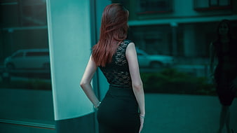 Redhead woman in black lace top standing in urban setting