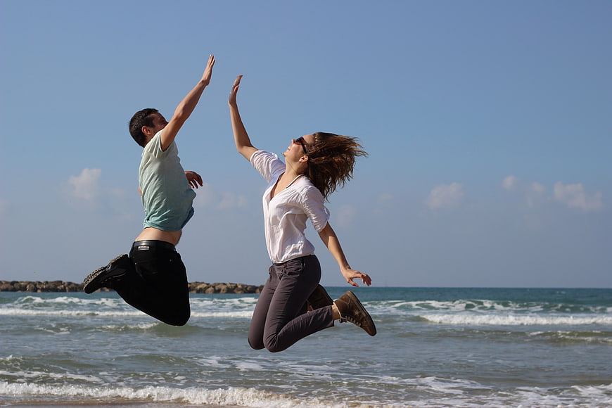 Happy couple jumping high on sunny beach