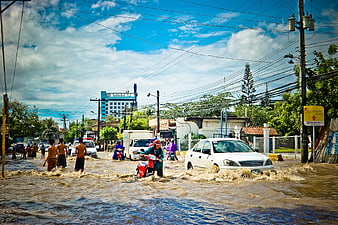 Flooded street with cars and motorcycles navigating through water