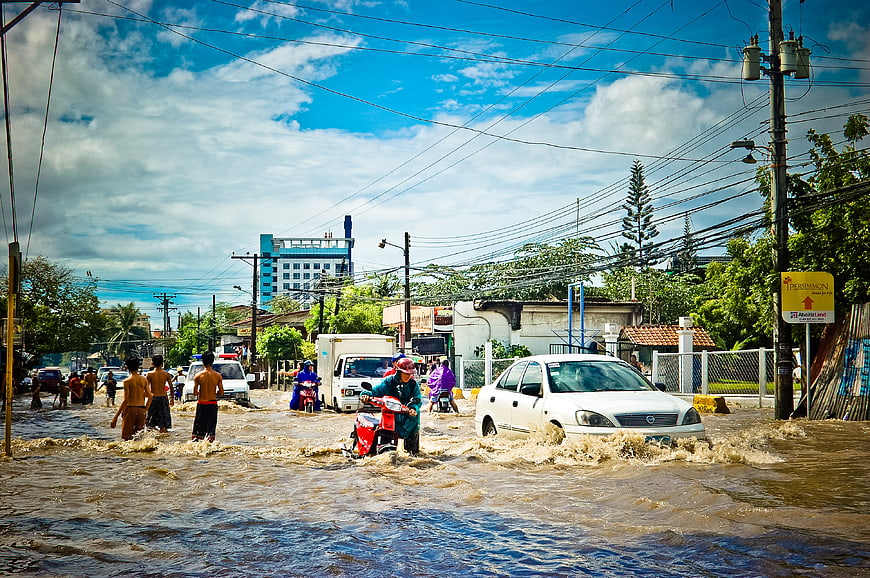 Flooded street with cars and motorcycles navigating through water