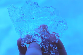 Hand holding chunk of blue ice close up
