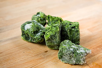 Frozen Spinach Blocks on Wooden Cutting Board
