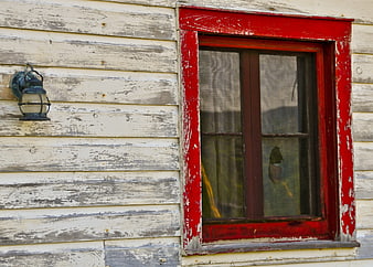 Rustic red window on weathered white wooden cabin wall