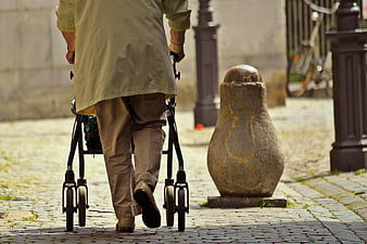 Senior woman walking with rollator on cobblestone street