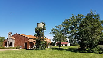 Red brick winery building with water tower and green lawn