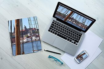 Laptop, smartphone, and print mockup of a harbor cityscape on a white wooden desk.