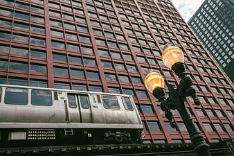 Low angle view of elevated subway train passing red brick building