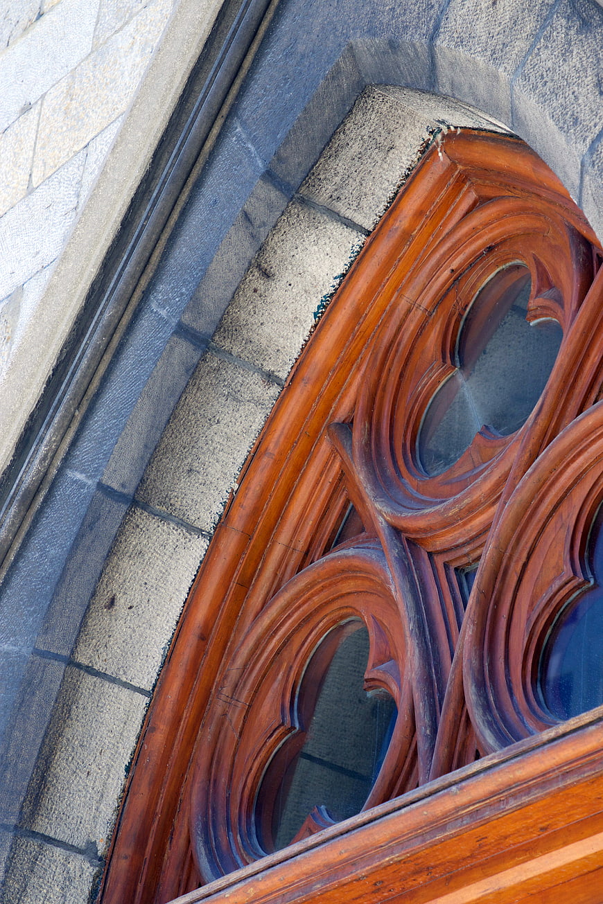 Close-up of ornate wooden window frame on stone church facade