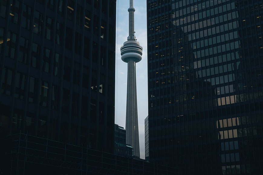 CN Tower framed between dark skyscrapers in Toronto