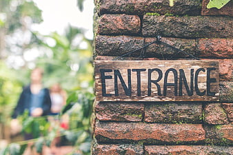 Rustic Wooden Entrance Sign on Mossy Brick Wall