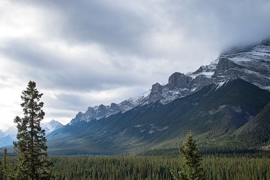 Majestic Snow-Capped Mountain Range with Forest and Clouds