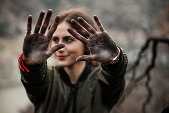 Woman with dirty hands reaching forward outdoors