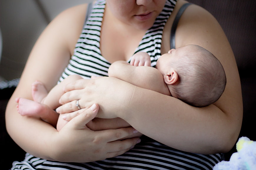 Mother holding newborn baby in striped top