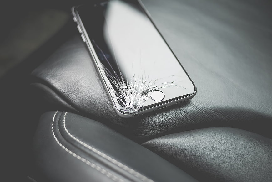 Cracked Smartphone Screen on Black Leather Surface