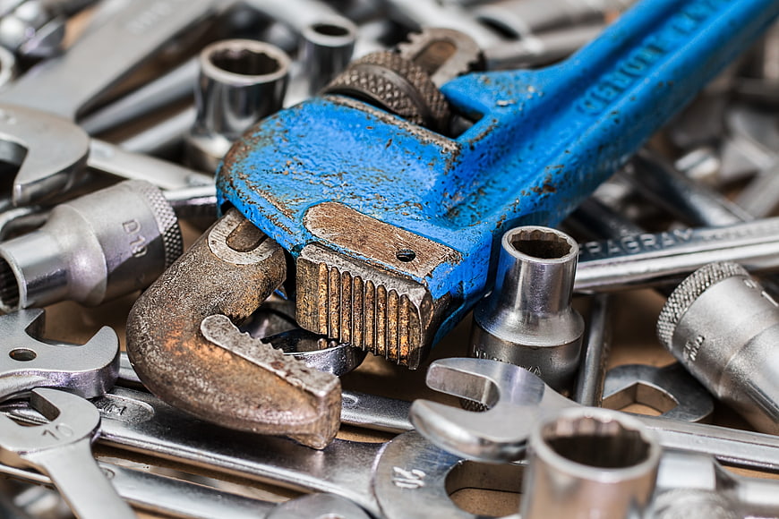 Close-up of worn blue pipe wrench and metal tools