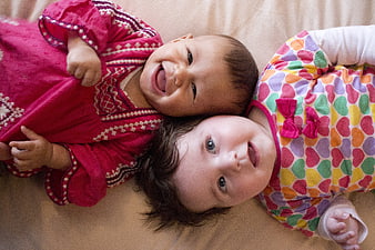 Two Happy Babies Lying Down Smiling and Laughing