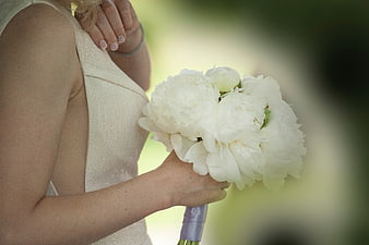 Bride holding white peony bouquet in wedding dress