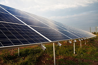 Row of solar panels in a field under a cloudy sky