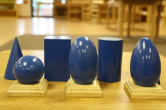 Blue geometric solids on wooden bases in a classroom