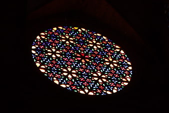 Illuminated circular stained glass window in dark interior