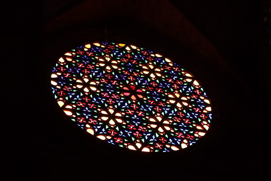 Illuminated circular stained glass window in dark interior