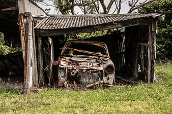 Rusty vintage car wreck in dilapidated wooden shed