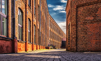 Historic Red Brick Industrial Factory Facade With Cobblestone Alley