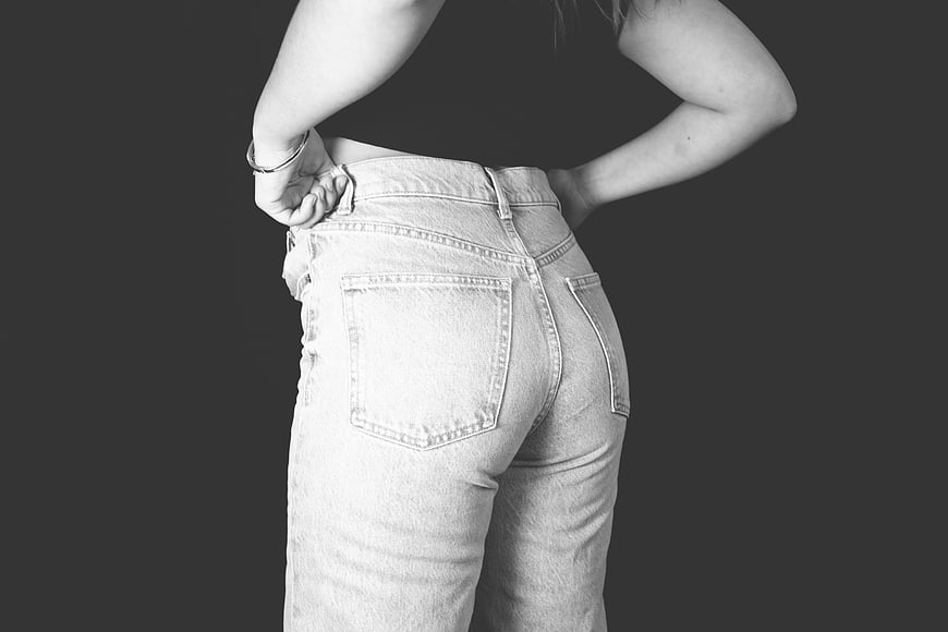 Woman in oversized jeans pulling waistband black and white