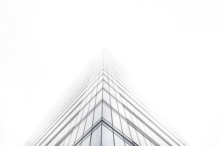 Low angle view of modern glass skyscraper disappearing into fog