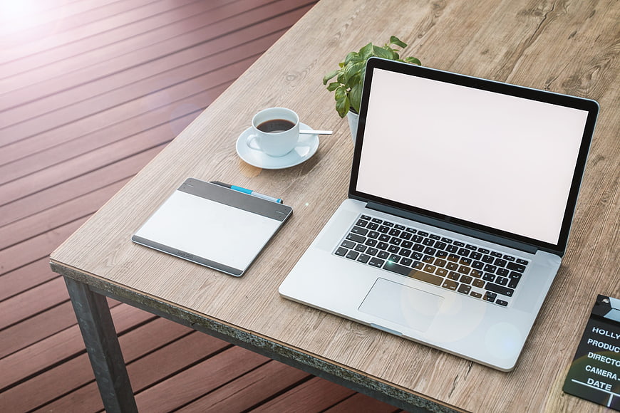 Laptop workspace mockup with coffee and notebook on wooden table