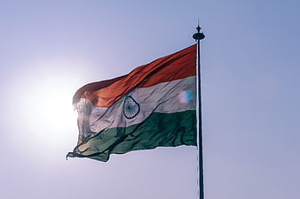 Indian Flag Waving Against Blue Sky with Sun Flare