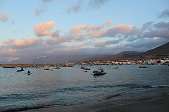 Boats in a calm harbor at sunset with mountains